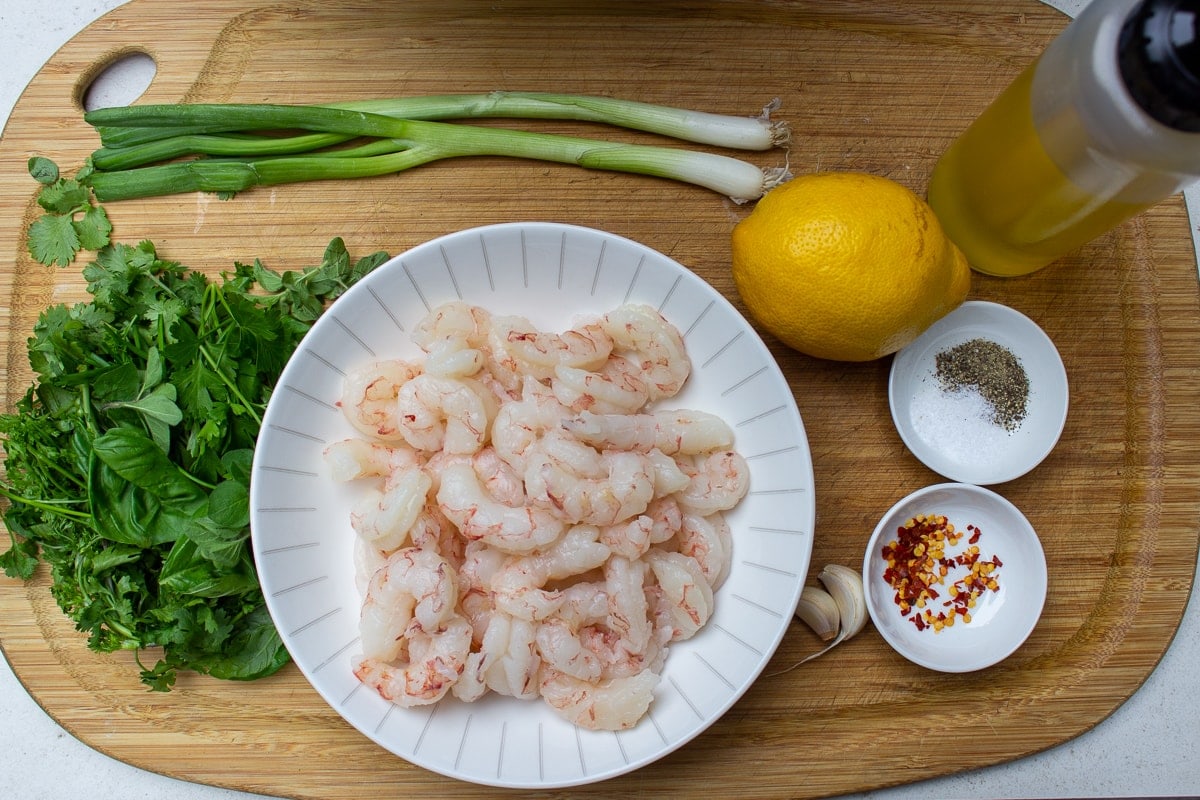 bowl or raw shrimp, green onions, herbs, spices, lemon, oil