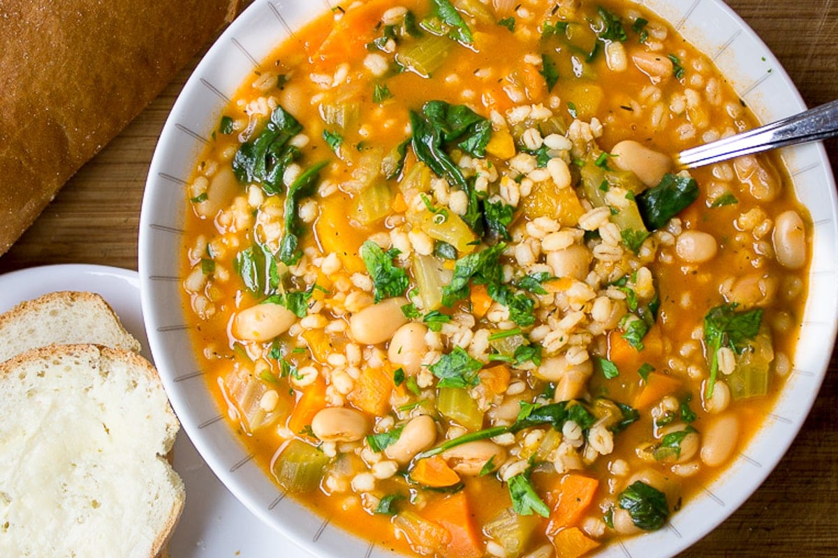 Vegetable Bean and Barley Soup in bowl with bread and butter f