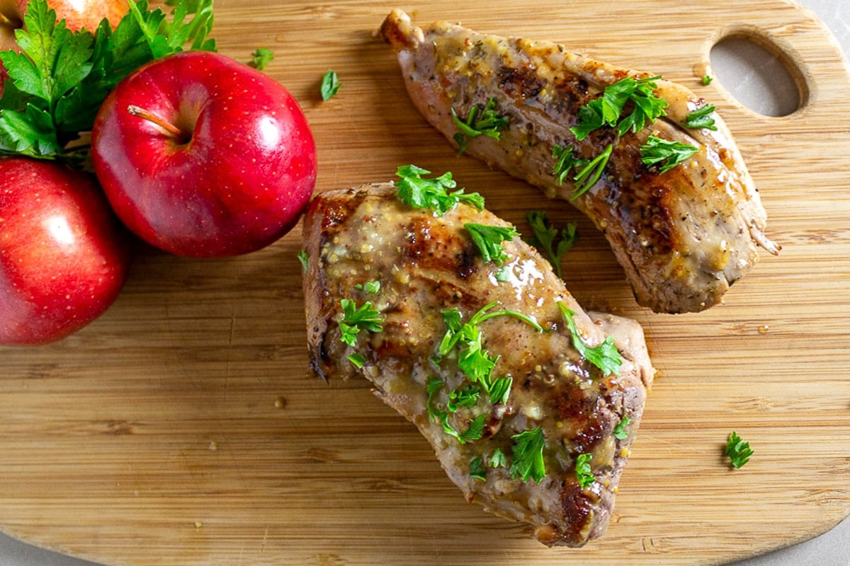 seared pork tenderloin on cutting board with apples