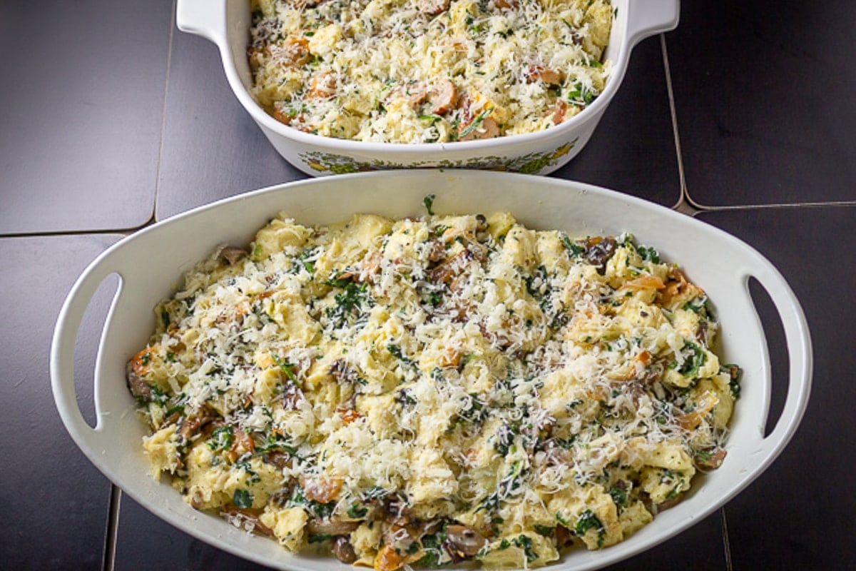 strata mixture in 2 casserole dishes with grated cheese on top