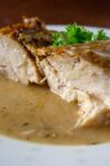 Instant Pot Roast Chicken breast meat cut in half on plate with gravy