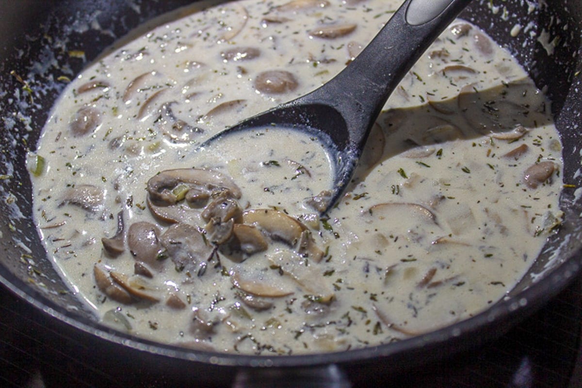 cream added to mushrooms and onions in pan