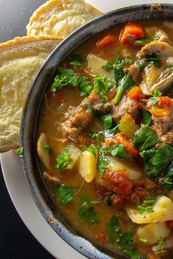 instant pot veal stew in a bowl with bread and butter
