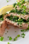cut open fillet of oasted Salmon Stuffed With Herbs on plate with lemon wedge p