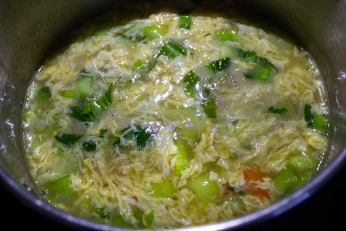 egg ribbons added to vegetable egg drop soup in pot