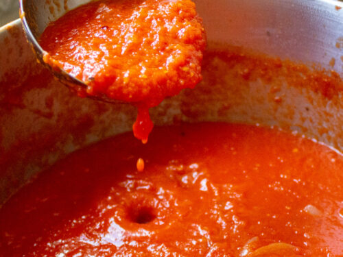 ladel full of san marzano tomato sauce over a pot