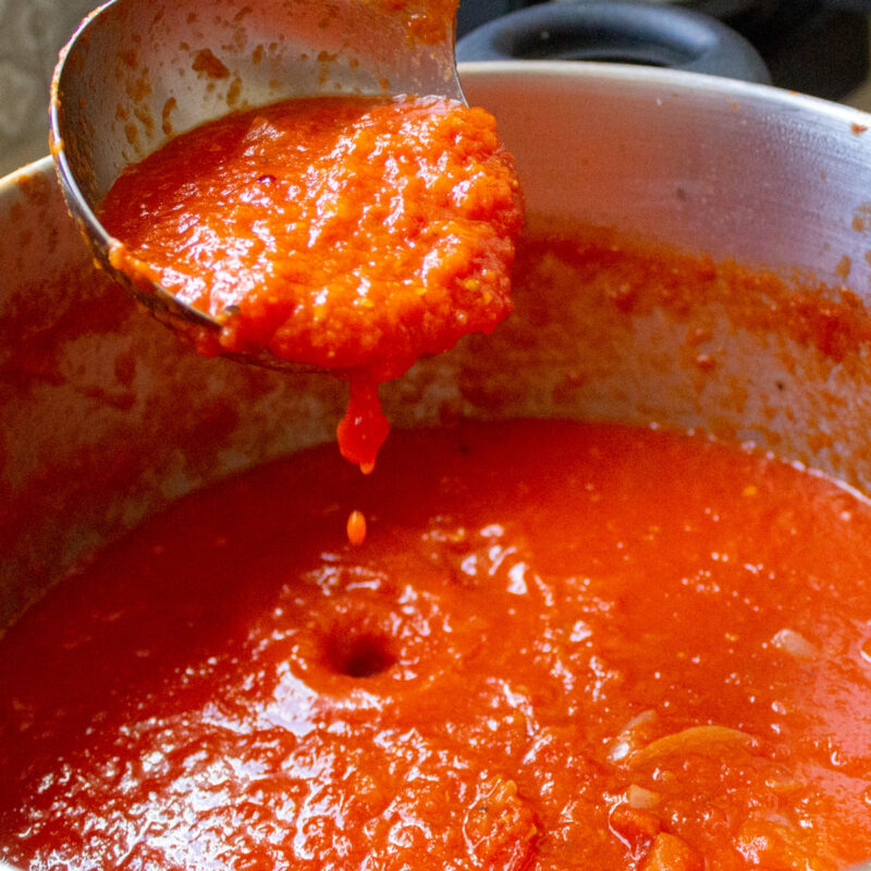 ladel full of san marzano tomato sauce over a pot