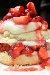 Strawberry Shortcake on plate with fresh biscuit cut in half filled with whipped cream and strawberries
