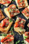 cut up Puff Pastry Tomato Tart cut into 3 inch squares on cutting board