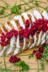 sliced grilled turkey breast on cutting board with cranberry relish on top