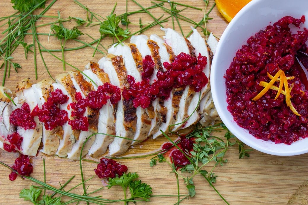 turkey breast cut in slices on cutting board, drizzled with cranberry relish sauce