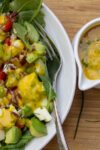 Mango Salad Dressing on salad in bowl with extra pitcher of dressing beside it p1