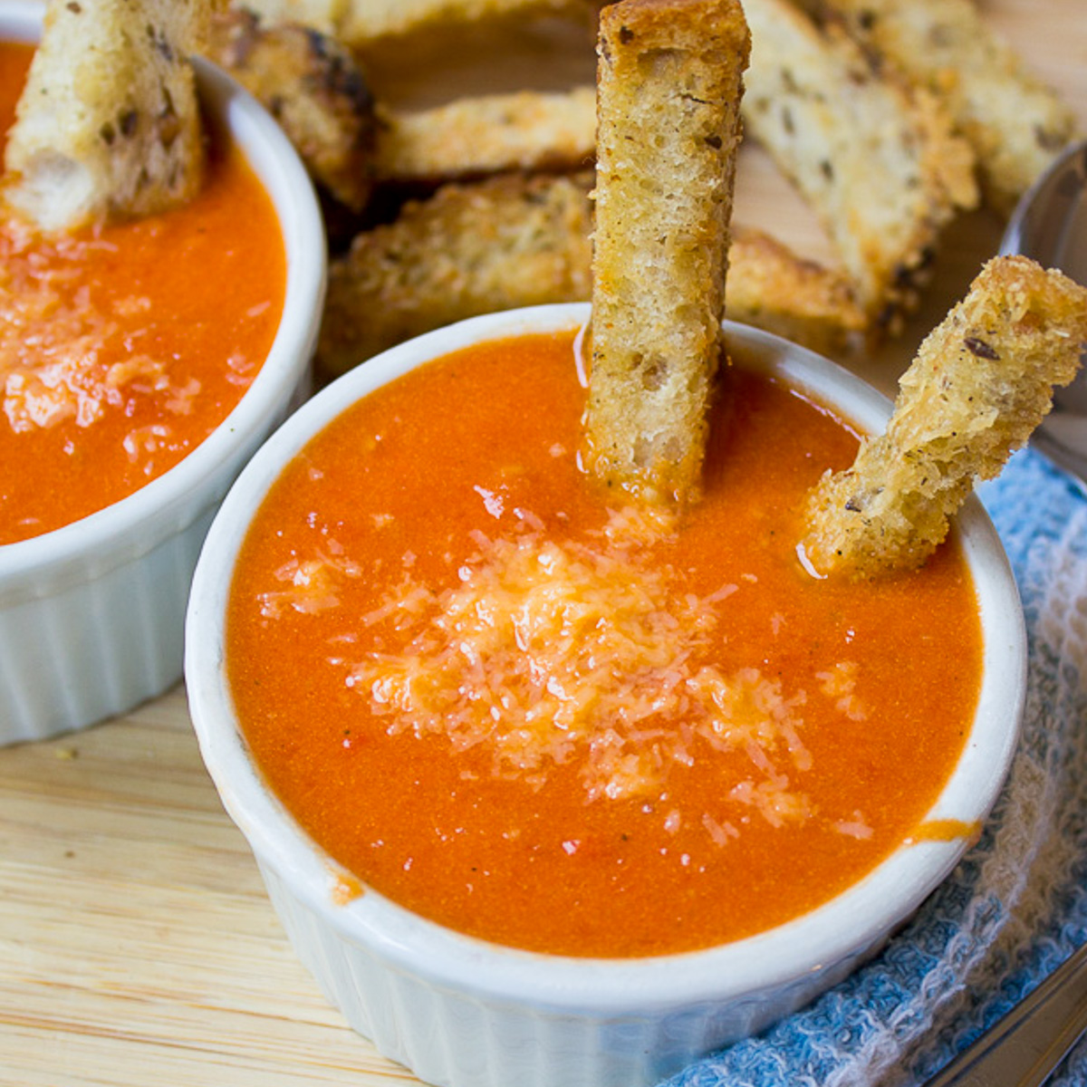 two bowls of tomato soup with crouton sticks