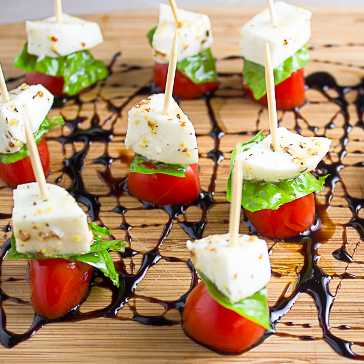 mini caprese appetizers on toothpicks on wood board