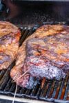 two briskets cooking in the smoker sitting on the grill p