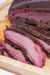 sliced smoked brisket on a cutting board showing pink smoke ring at edges p1
