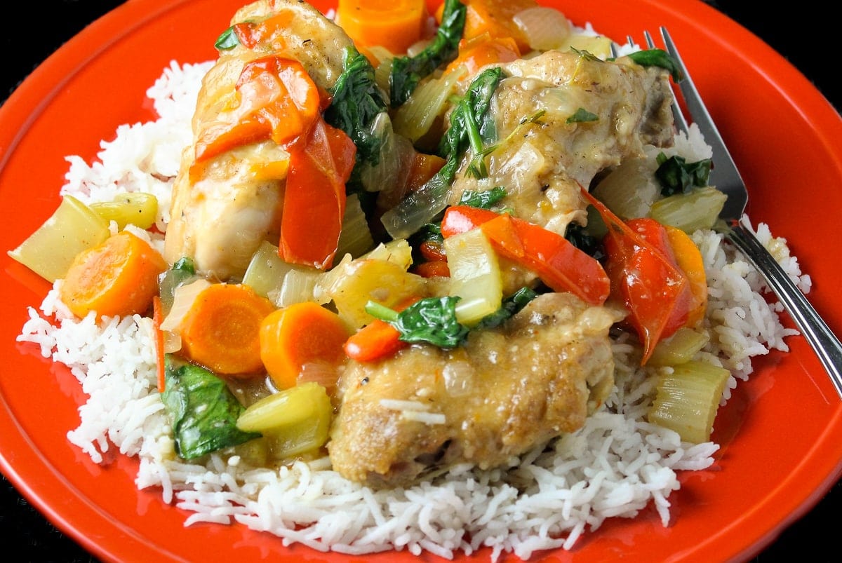 chicken and vegetables in sauce on plate with rice