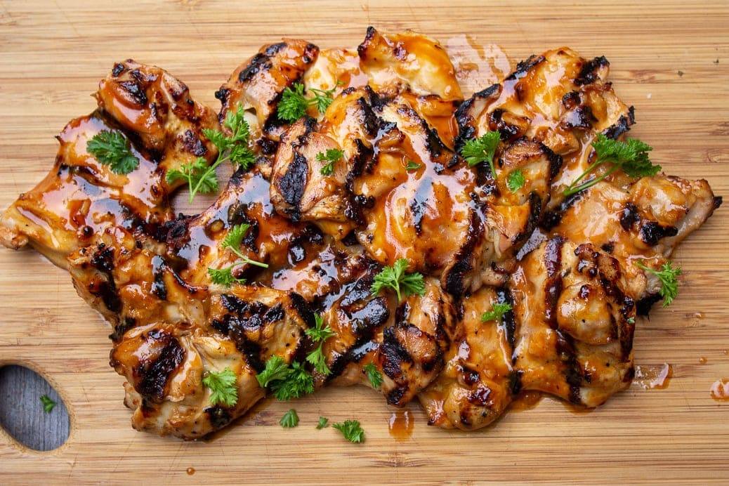 Grilled BBQ boneless Chicken thighs on cutting board