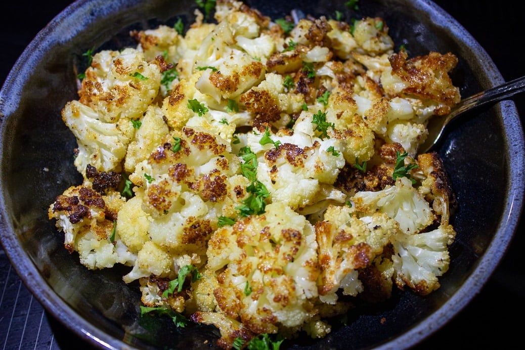 Parmesan roasted cauliflower in a serving bowl sprinkled with parsley