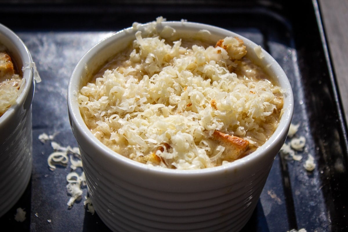 grated cheese on bread cubes in bowl before broiling