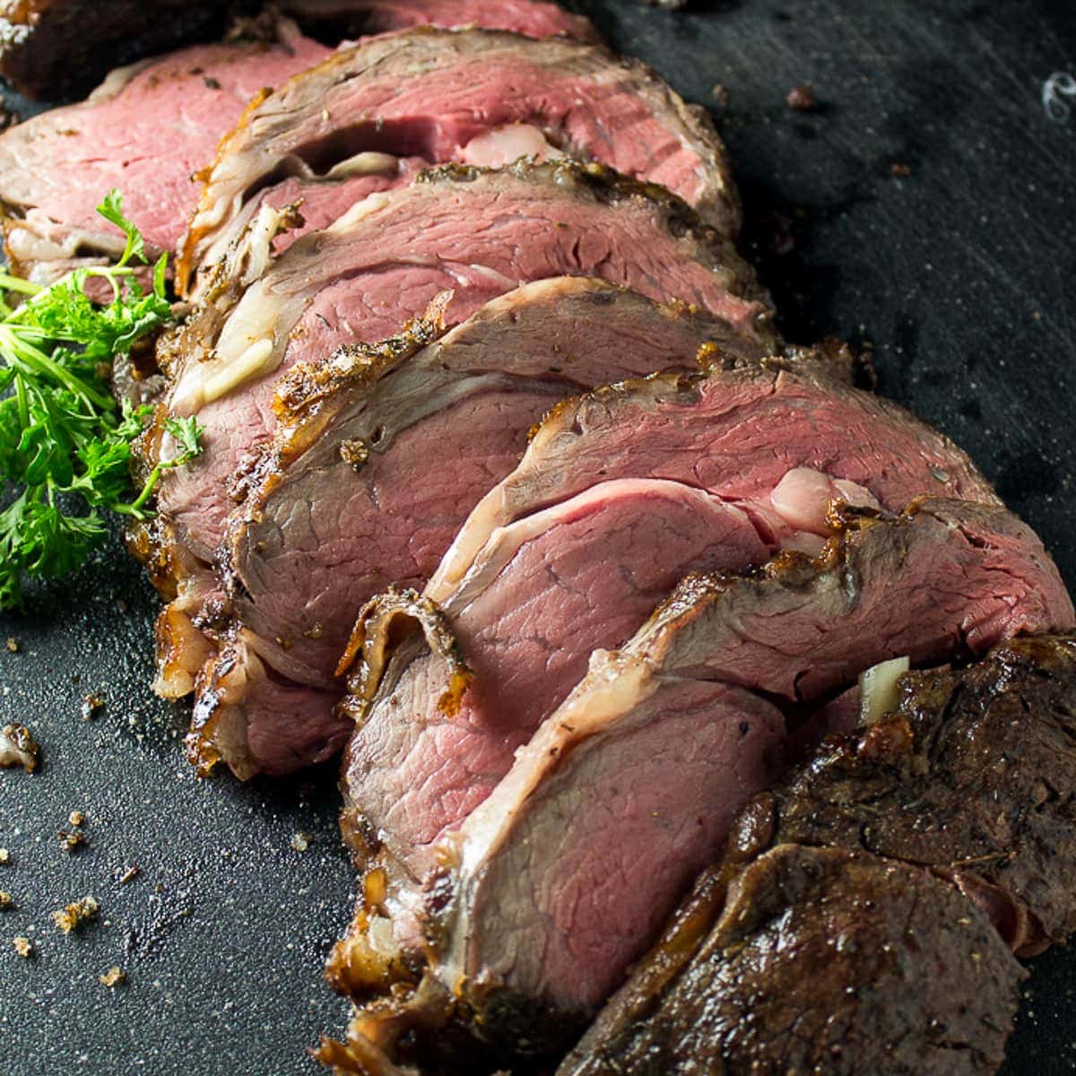 medium rare classic prime rib reverse sear sliced on cutting board