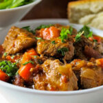 veal stew in bowl with bread and salad