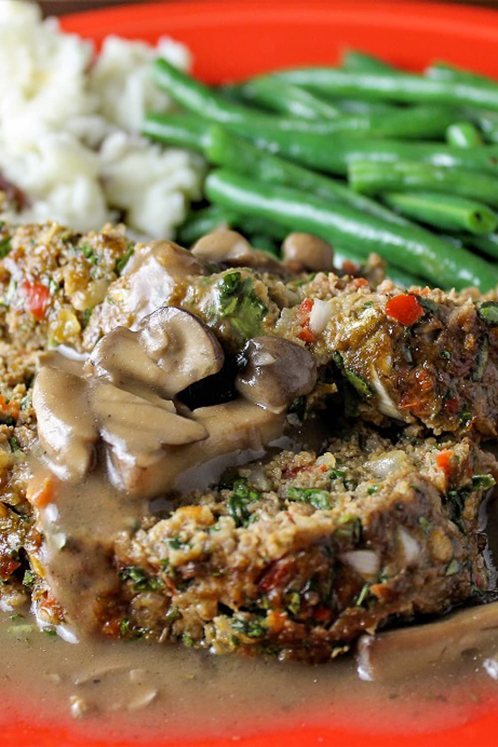 slices of meatloaf with mushroom gravy on plate with veggies p