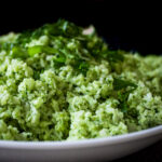 Cauliflower rice with pesto in a bowl garnished with basil.