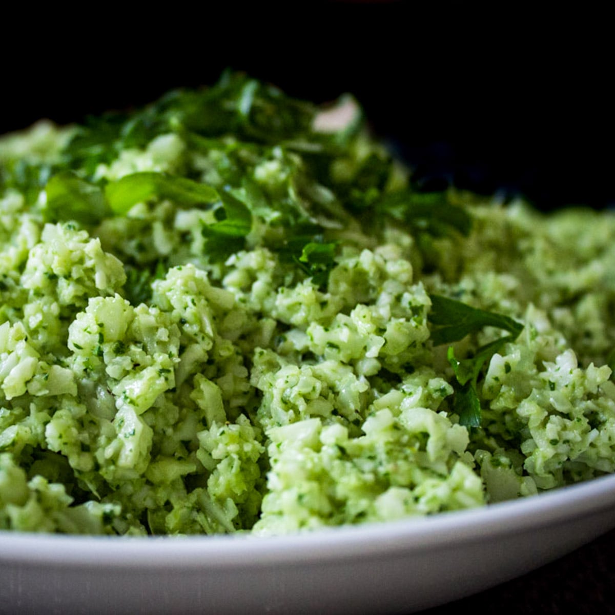 Cauliflower rice with pesto in a bowl garnished with basil.
