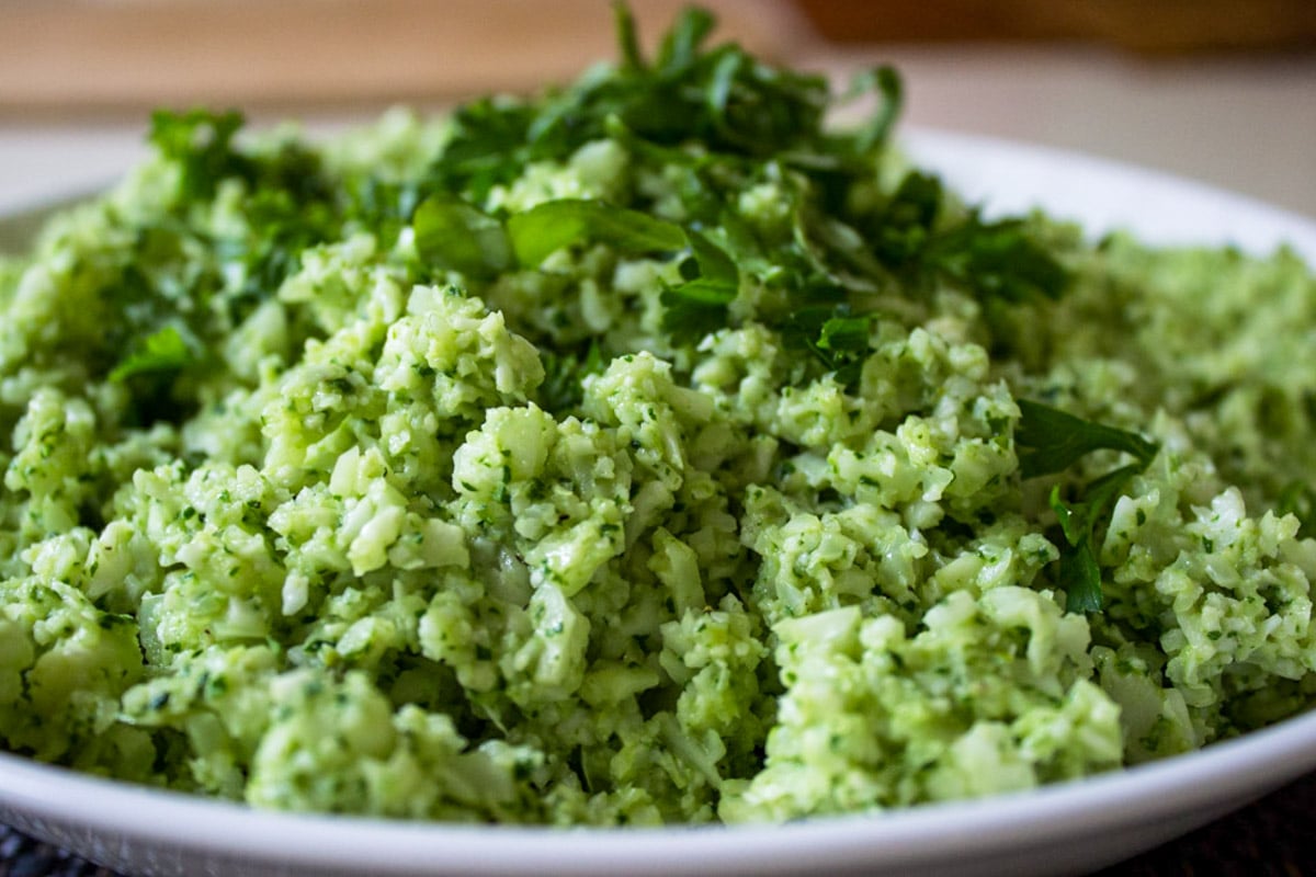 Cauliflower rice with pesto in a bowl garnished with basil.