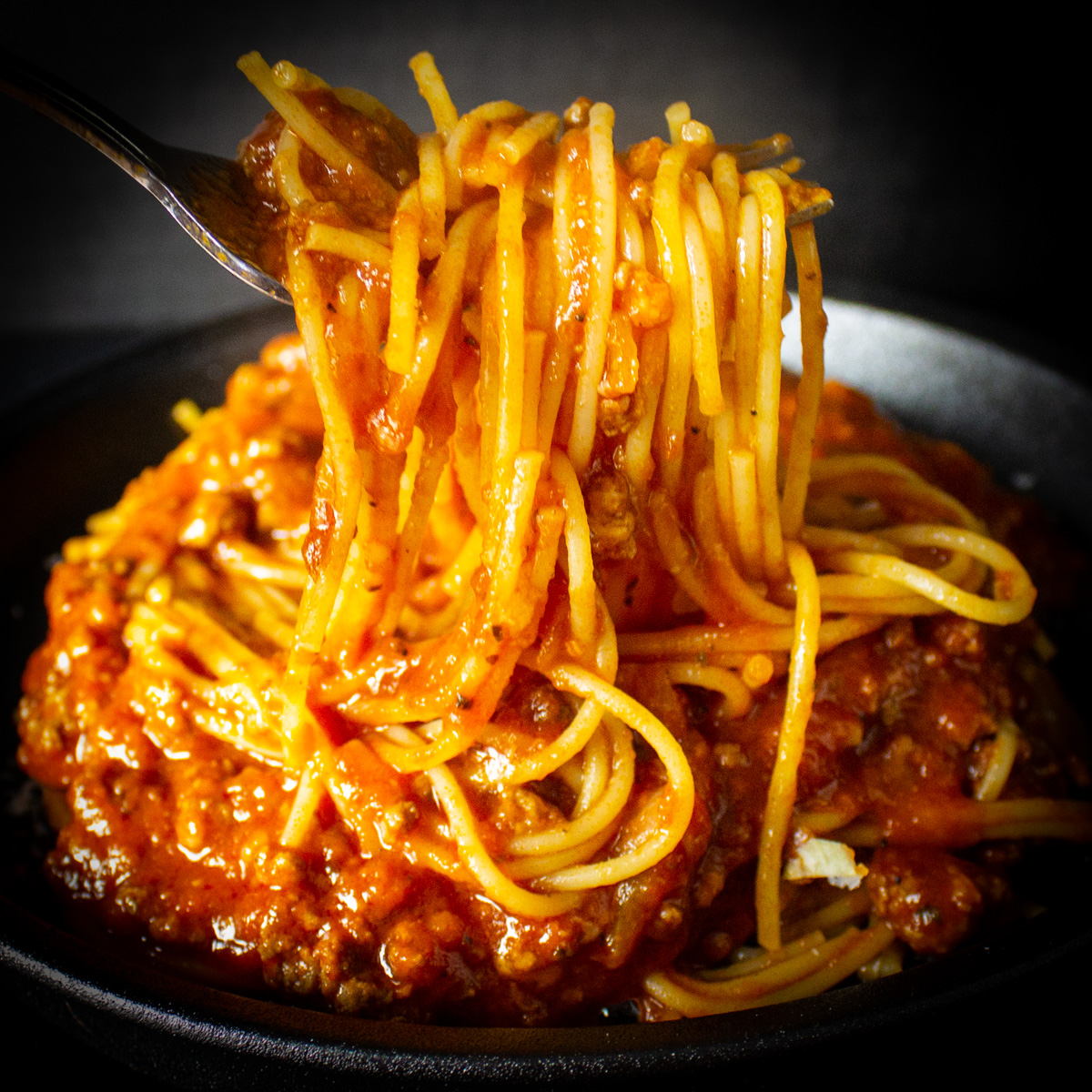 plate of spaghetti with fork lifting some up