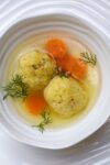 bowl of chicken soup with matzo balls and carrots p