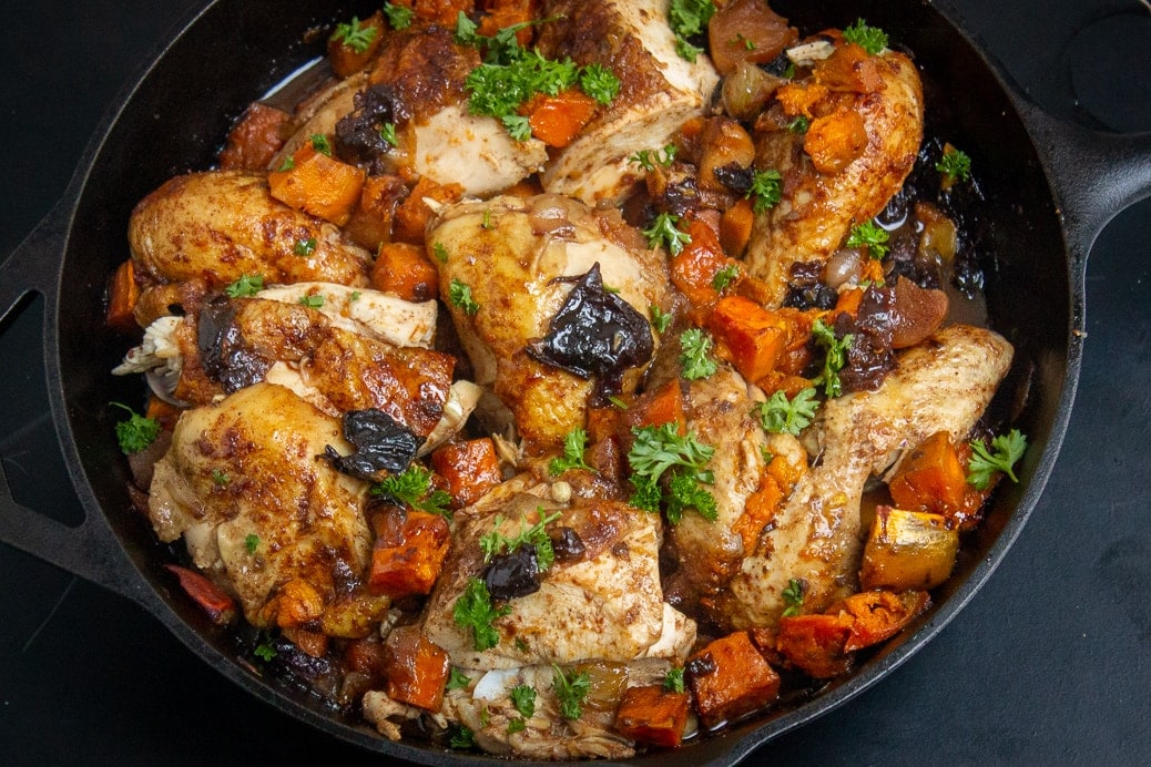 cut up Moroccan roast chicken with sweet potatoes in a skillet f