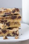 four chocolate chip cookie bars stacked on plate with milk beside it p2