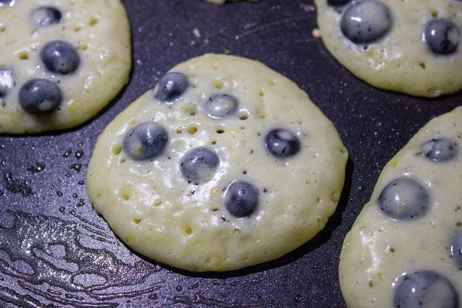 close up of pancake in pan with bubbles forming on top