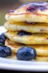 stack of lemon blueberry pancakes in plate with syrup on top and fresh blueberries p