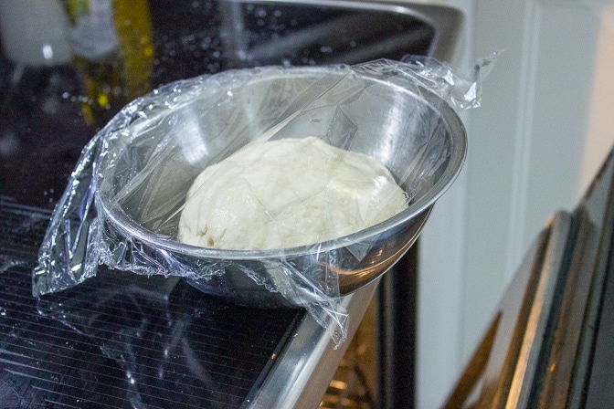 dough in bowl covered sitting on stove to rise