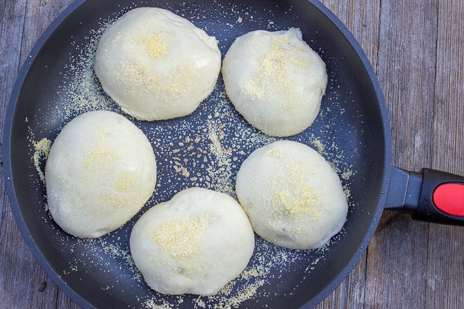 5 pieces of english muffin dough in pan