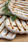 several grilled naan on cutting board p