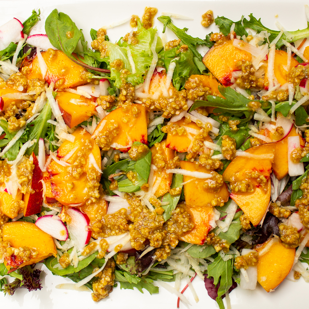 peach salad with walnut dressing on white plate