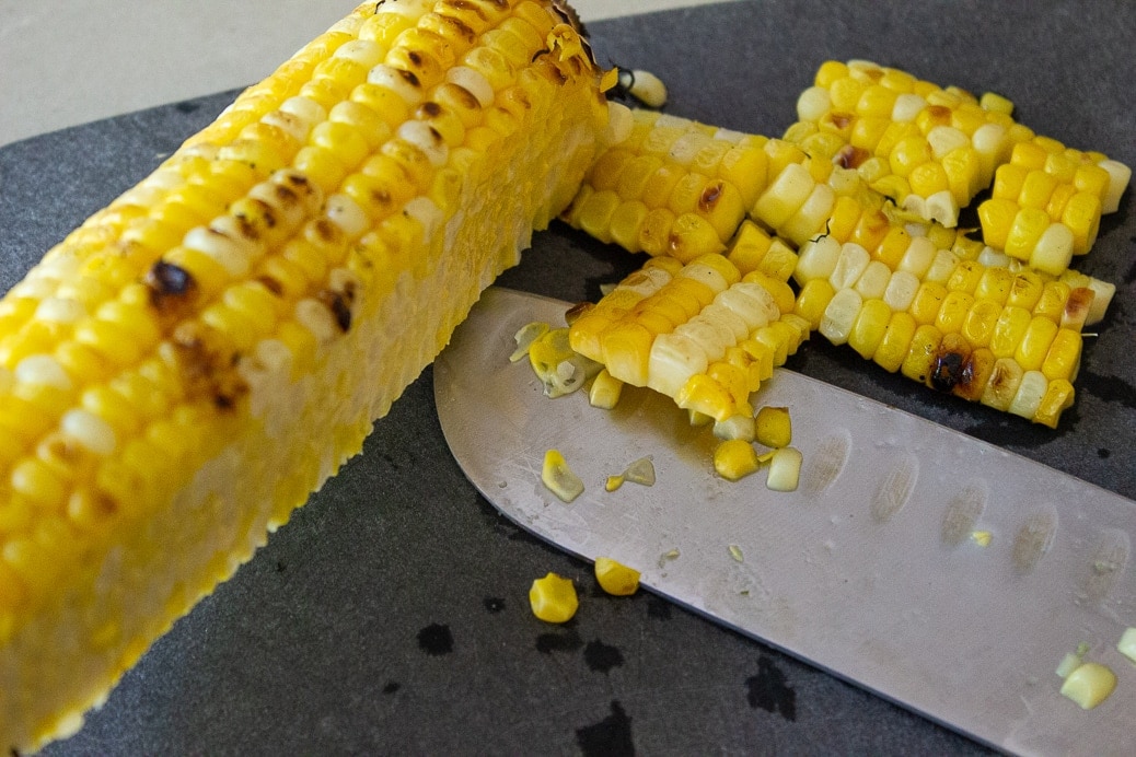 cutting kernals off cob of corn with knife