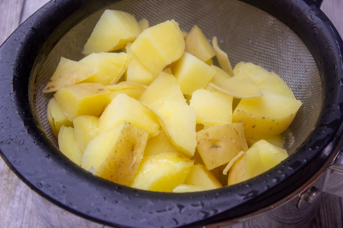 boiled potatoes draining in colander.