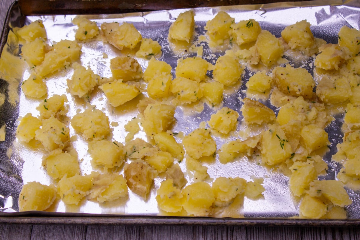 boiled potatoes with butter and seasoning on foil lined pan.