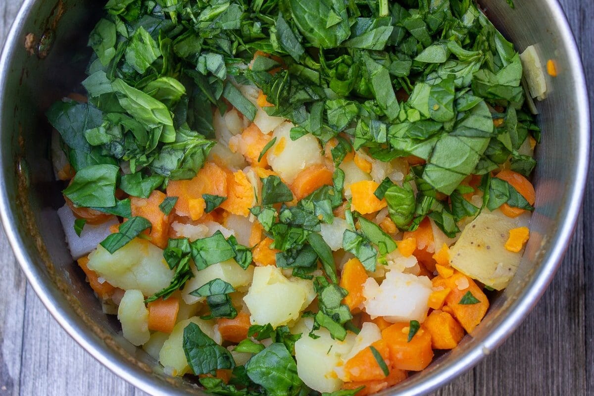 cooked root vegetables and chopped spinach in pot