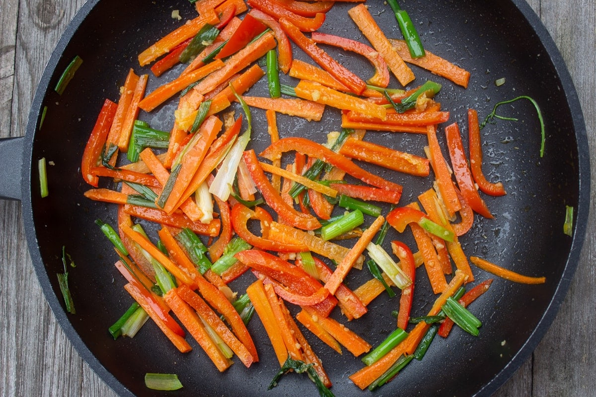 peppers, carrots, green onions, garlic in pan