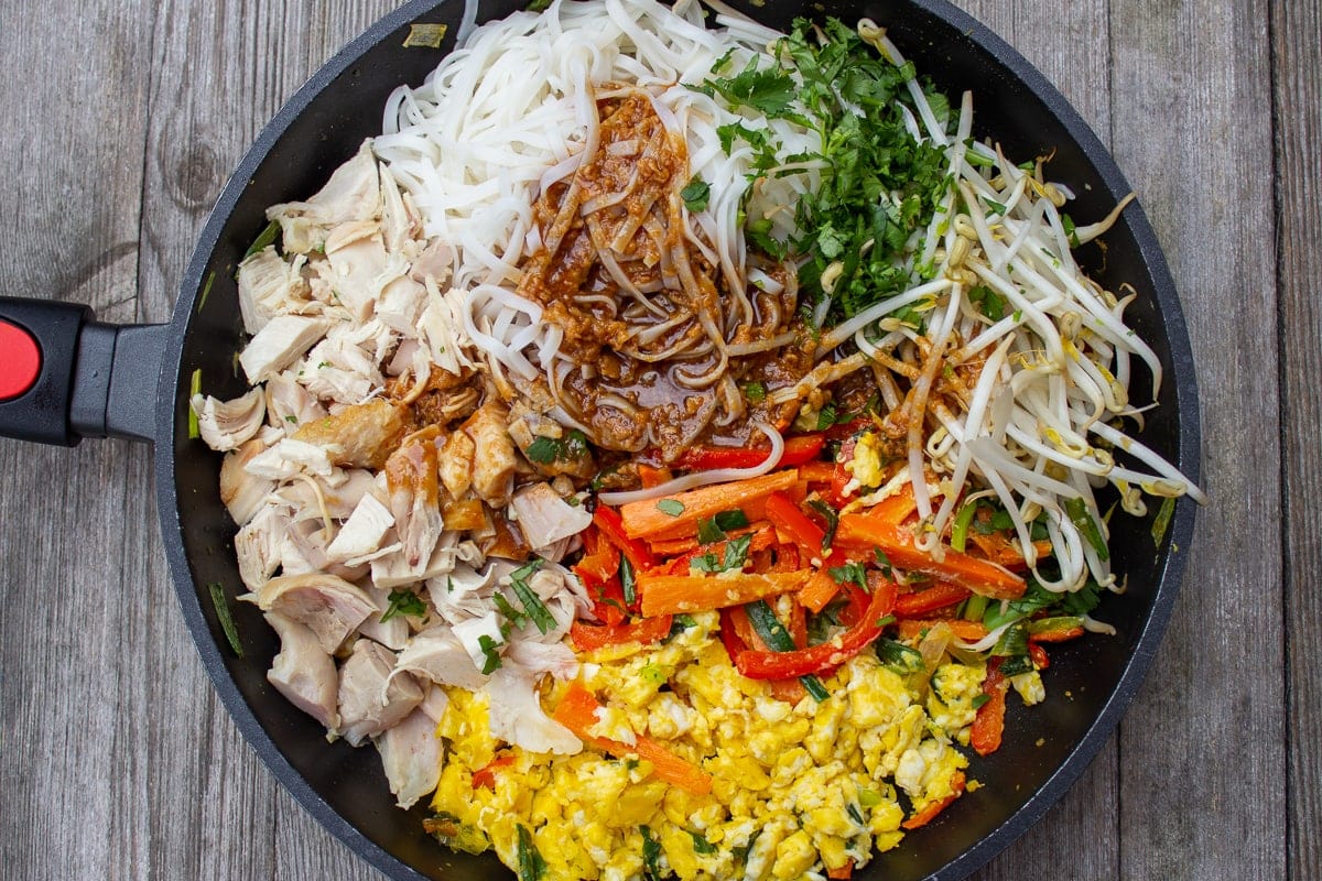 all pad thai ingredients in pan with sauce on top