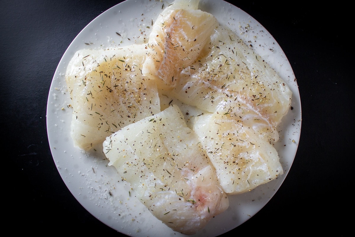 uncooked cod fish fillet pieces on plate