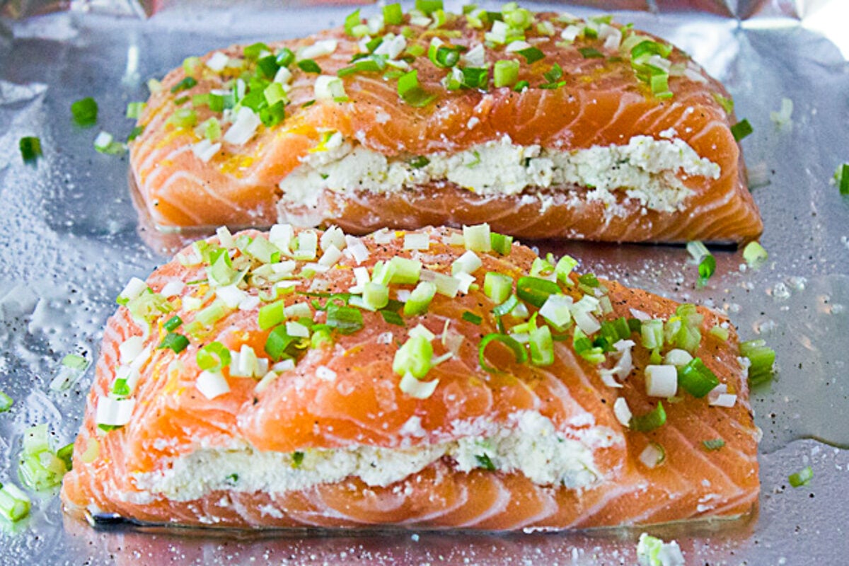 two salmon fillets uncooked and stuffed with ricotta mixture on foil lined pan.