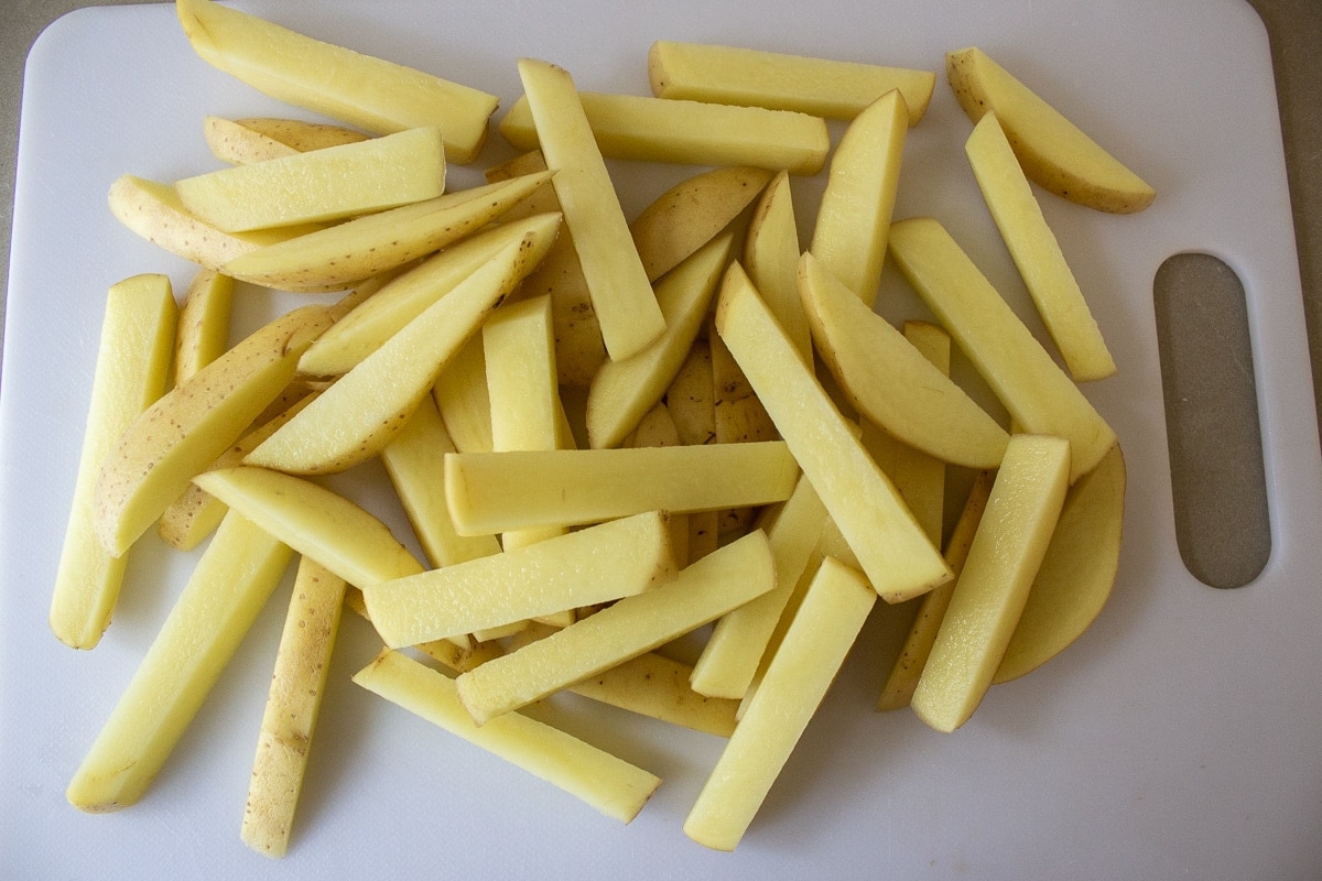 potatoes cut into fries on cutting board