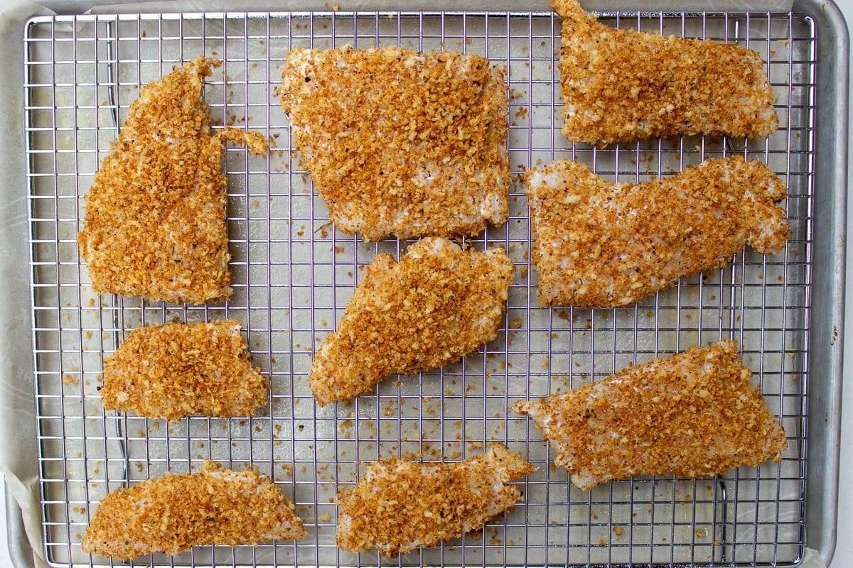 uncooked fish pieces breaded on rack over pan